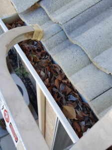 clogged rain gutters filled with sand, sludge, and leaves.